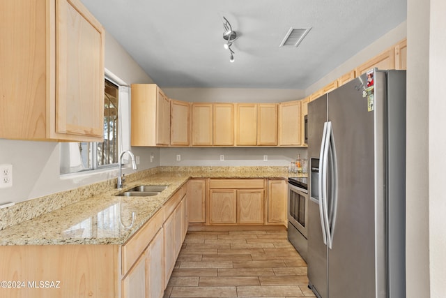 kitchen featuring light stone counters, light brown cabinetry, sink, light hardwood / wood-style floors, and stainless steel appliances