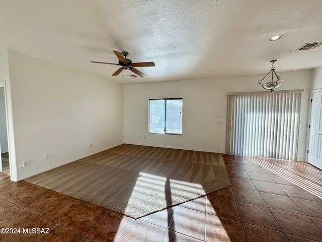 empty room with dark tile patterned flooring, ceiling fan, and a textured ceiling