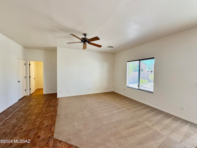 empty room with dark colored carpet, a textured ceiling, and ceiling fan