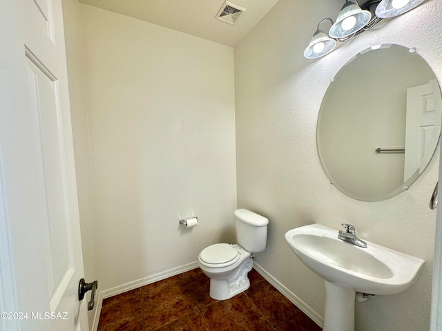 bathroom with toilet, sink, and tile patterned floors