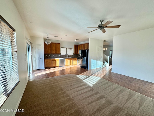 kitchen with decorative backsplash, black fridge, dishwasher, pendant lighting, and sink