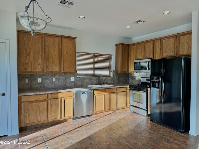 kitchen with hanging light fixtures, backsplash, sink, light tile patterned floors, and appliances with stainless steel finishes