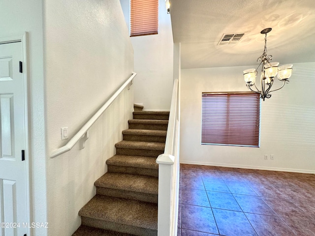 stairway featuring a notable chandelier and tile patterned flooring