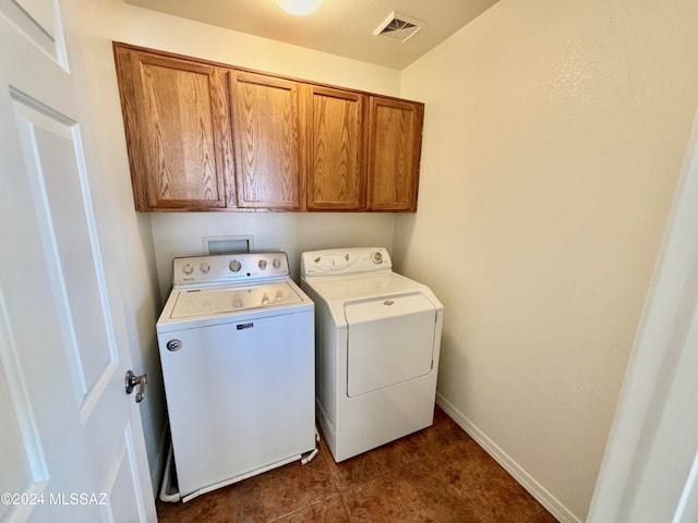 laundry room with washer and clothes dryer, dark tile patterned flooring, and cabinets