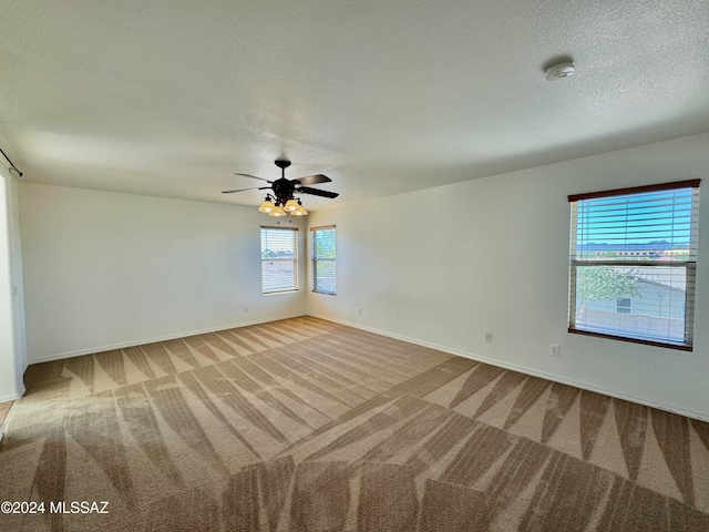 spare room featuring light carpet, a textured ceiling, and ceiling fan