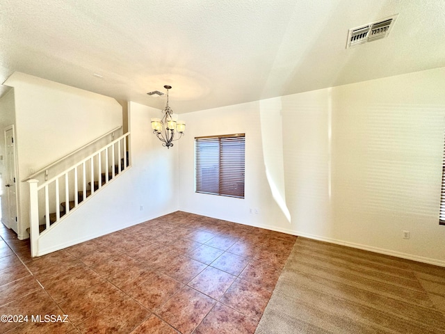 empty room with a chandelier and a textured ceiling