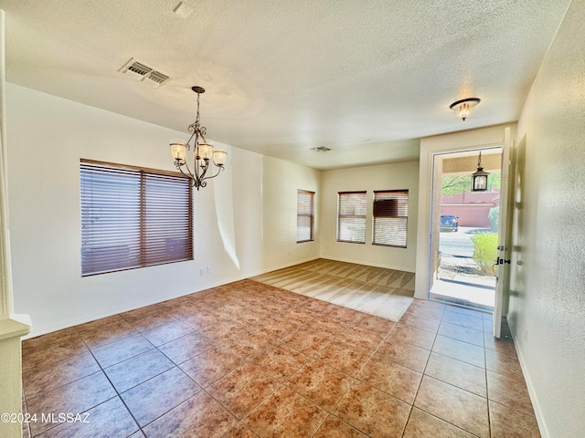 entrance foyer with a textured ceiling, an inviting chandelier, and tile patterned flooring