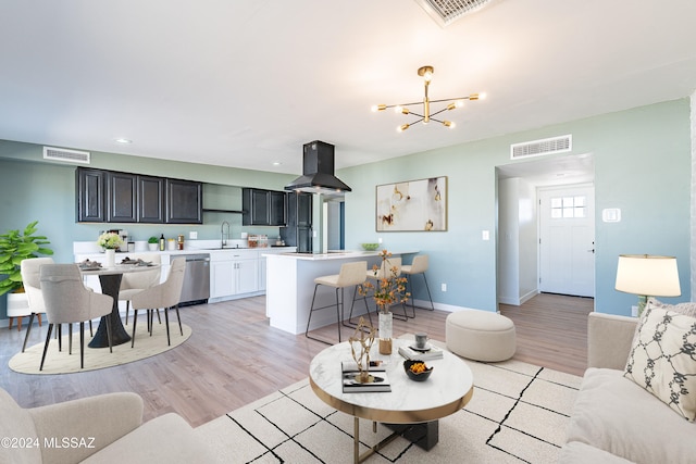 living room featuring a chandelier, sink, and light hardwood / wood-style floors