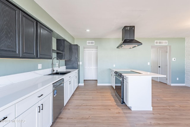 kitchen featuring white cabinets, extractor fan, appliances with stainless steel finishes, light hardwood / wood-style flooring, and sink