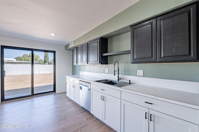 kitchen featuring light stone countertops, sink, dishwasher, light wood-type flooring, and white cabinets