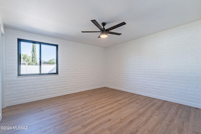 empty room featuring brick wall and light hardwood / wood-style flooring