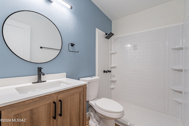 bathroom with vanity, toilet, and tiled shower