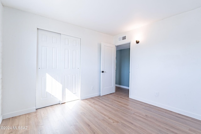 unfurnished bedroom featuring a closet and light wood-type flooring