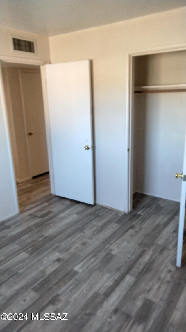 unfurnished bedroom featuring dark hardwood / wood-style floors and a closet