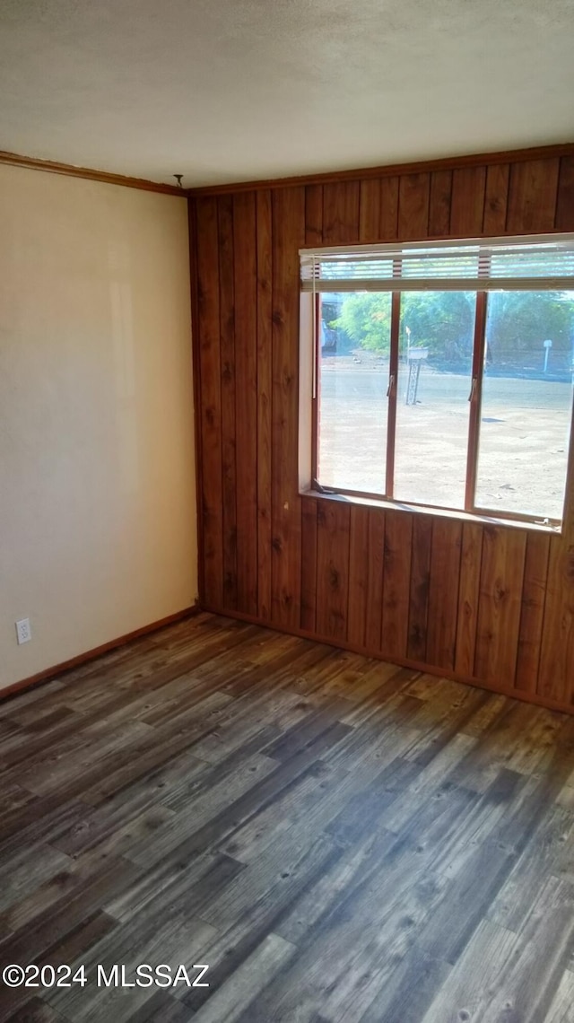 empty room featuring ornamental molding and dark wood-type flooring