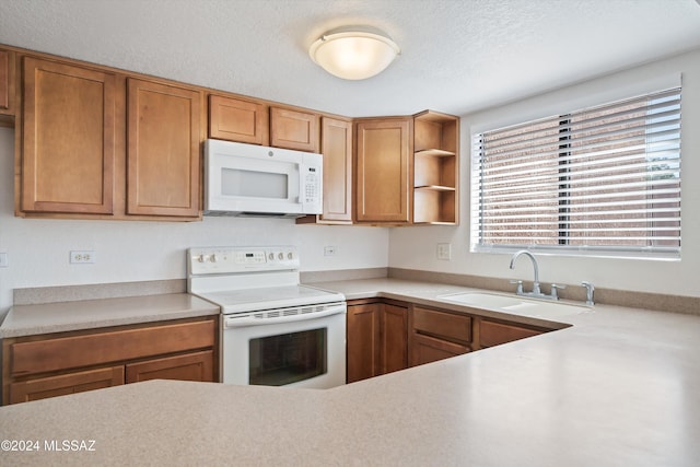 kitchen featuring a textured ceiling, sink, and white appliances