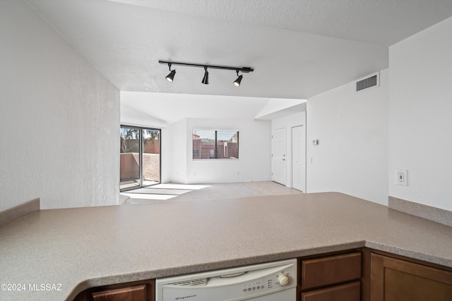 kitchen featuring dishwasher, a textured ceiling, rail lighting, and vaulted ceiling