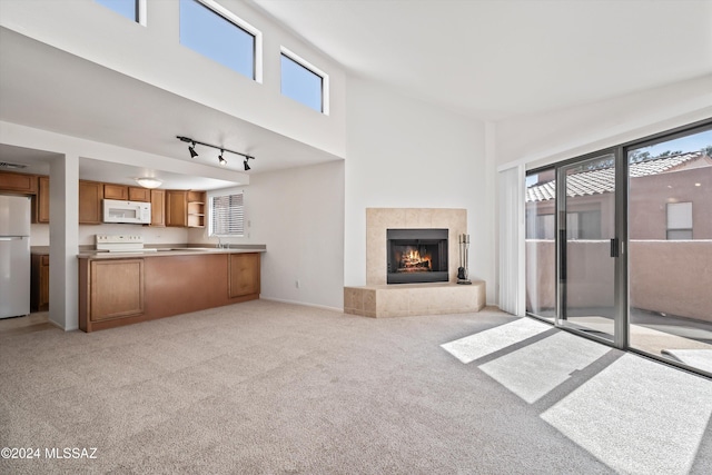 unfurnished living room featuring a tiled fireplace, sink, and light colored carpet