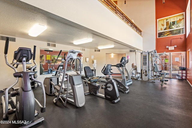 workout area with a high ceiling and a textured ceiling