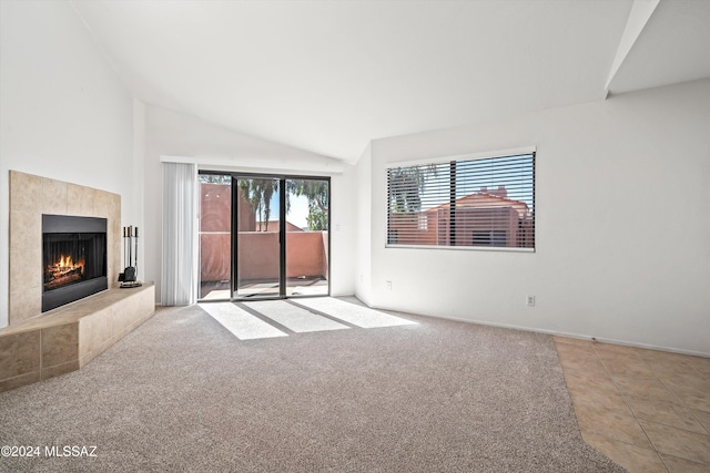 unfurnished living room featuring lofted ceiling, a fireplace, and light carpet