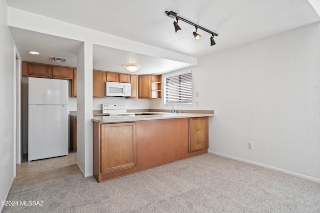 kitchen with kitchen peninsula, light carpet, track lighting, and white appliances