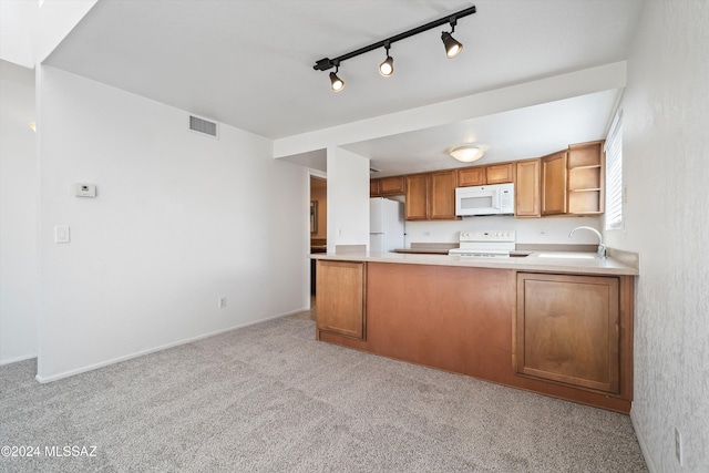 kitchen with kitchen peninsula, light carpet, white appliances, and sink