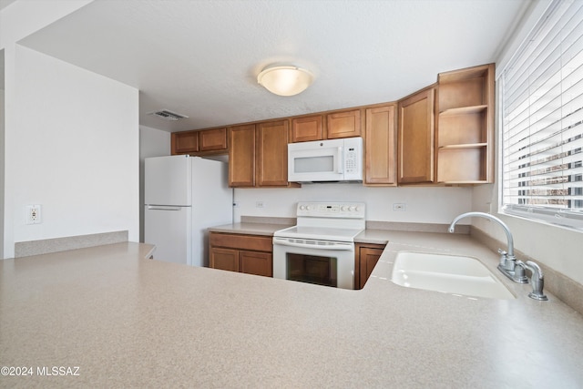 kitchen with kitchen peninsula, white appliances, and sink