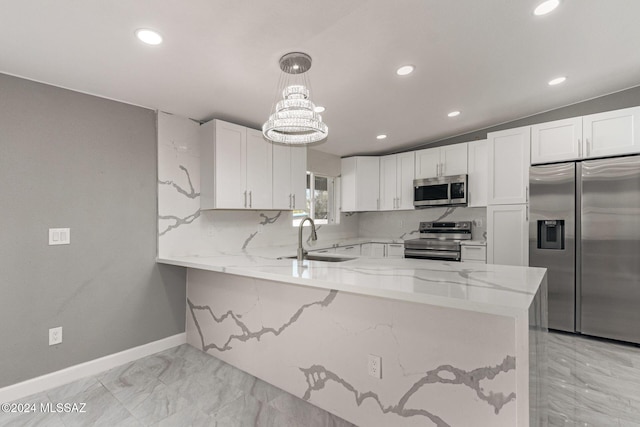 kitchen featuring kitchen peninsula, sink, pendant lighting, white cabinetry, and appliances with stainless steel finishes