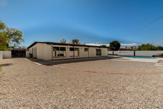 back of property featuring a fenced in pool and a patio