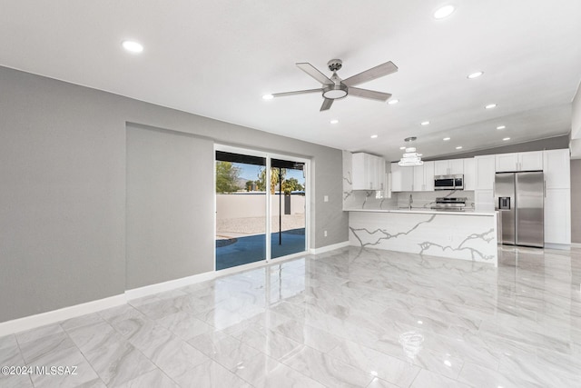 interior space featuring kitchen peninsula, white cabinets, ceiling fan, appliances with stainless steel finishes, and light stone countertops