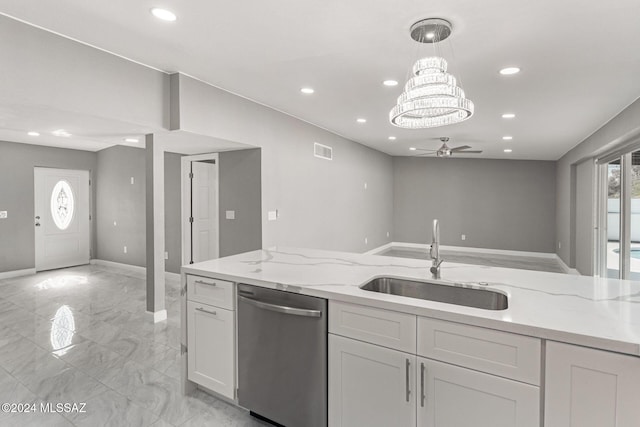 kitchen with light stone countertops, sink, dishwasher, white cabinetry, and decorative light fixtures