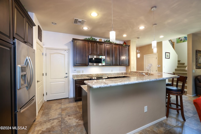 kitchen featuring a kitchen breakfast bar, kitchen peninsula, dark brown cabinets, pendant lighting, and appliances with stainless steel finishes