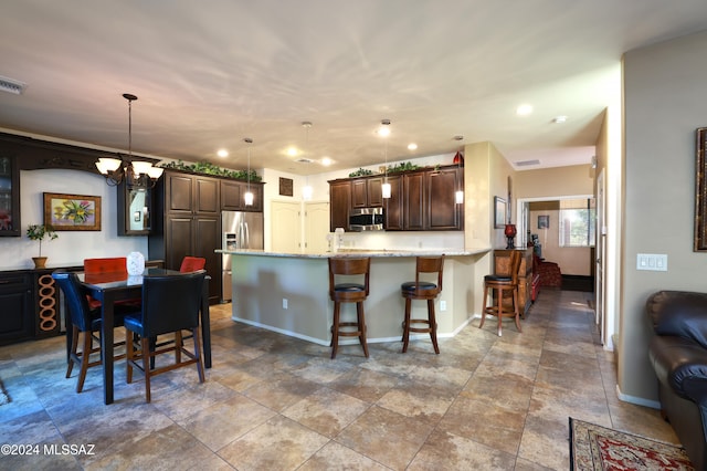 kitchen featuring dark brown cabinetry, light stone countertops, hanging light fixtures, and stainless steel appliances