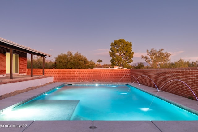 pool at dusk featuring pool water feature