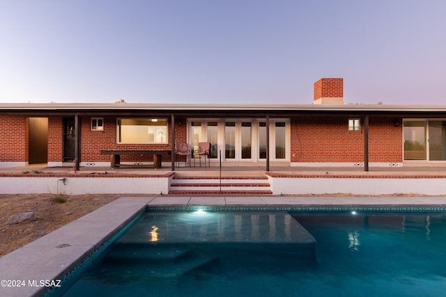 pool at dusk featuring a patio