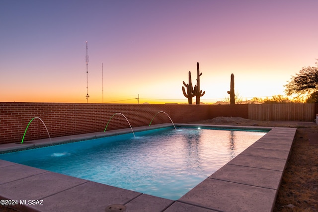 pool at dusk featuring pool water feature