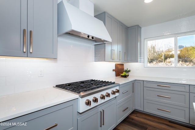 kitchen featuring custom exhaust hood, dark hardwood / wood-style floors, gray cabinetry, stainless steel gas cooktop, and light stone counters