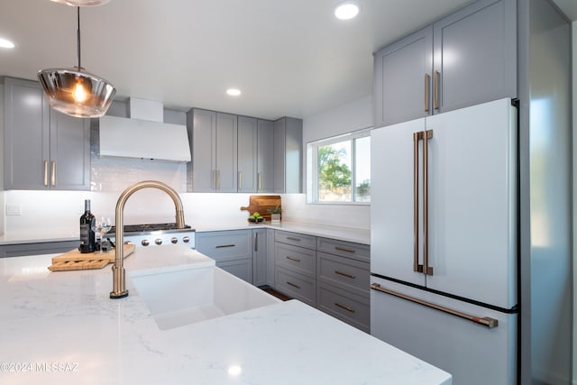 kitchen with gray cabinetry, light stone countertops, high end white refrigerator, and pendant lighting