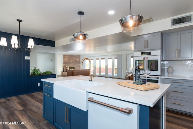 kitchen with tasteful backsplash, dark hardwood / wood-style flooring, a kitchen island with sink, pendant lighting, and sink