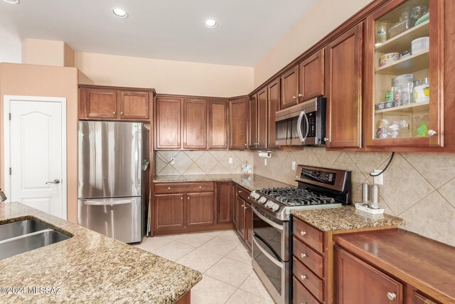 kitchen with light tile patterned floors, stainless steel appliances, light stone countertops, and sink