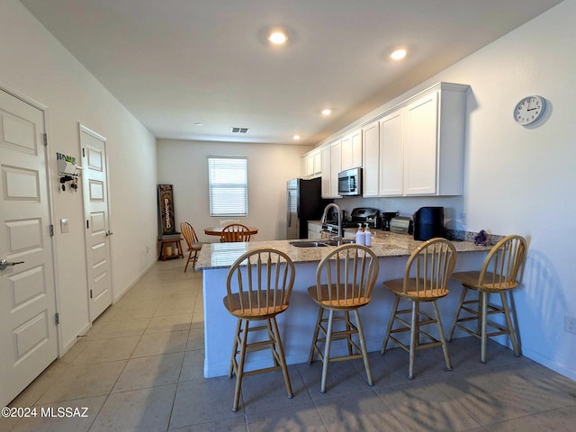 kitchen featuring appliances with stainless steel finishes, sink, kitchen peninsula, a kitchen breakfast bar, and white cabinets