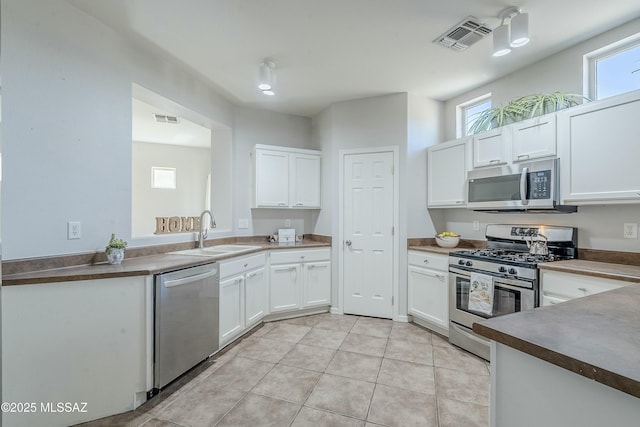 kitchen featuring white cabinetry, appliances with stainless steel finishes, sink, and light tile patterned floors