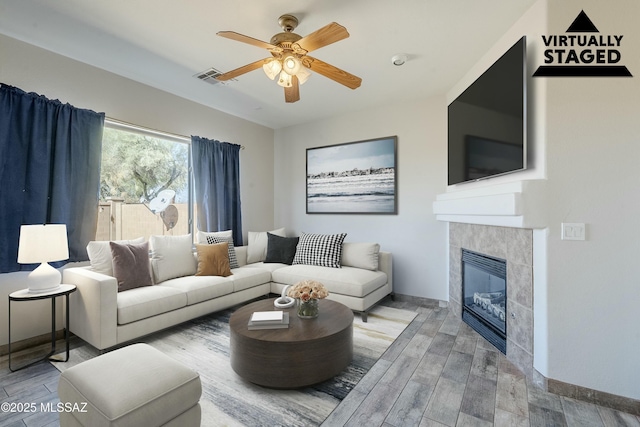 living room with hardwood / wood-style flooring, ceiling fan, and a fireplace