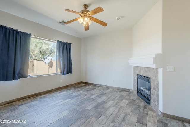 unfurnished living room featuring a tiled fireplace, light hardwood / wood-style flooring, and ceiling fan