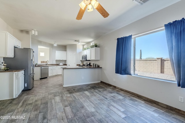 kitchen featuring white cabinets, ceiling fan, kitchen peninsula, stainless steel appliances, and light hardwood / wood-style flooring