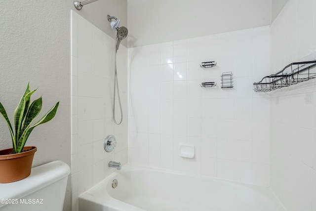 bathroom featuring tiled shower / bath combo and toilet