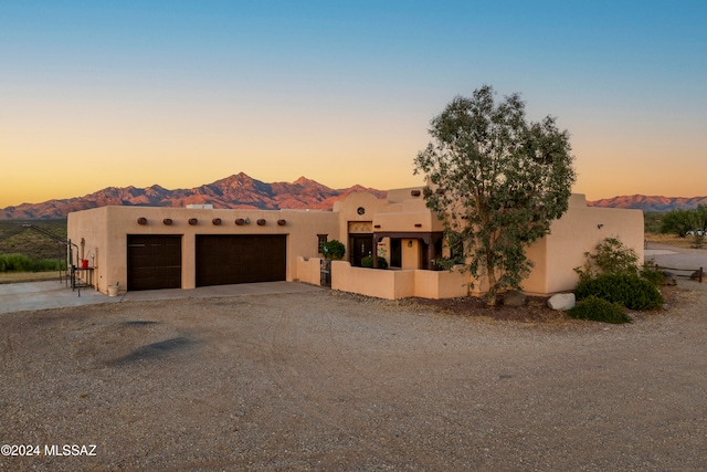 pueblo-style home with a garage and a mountain view