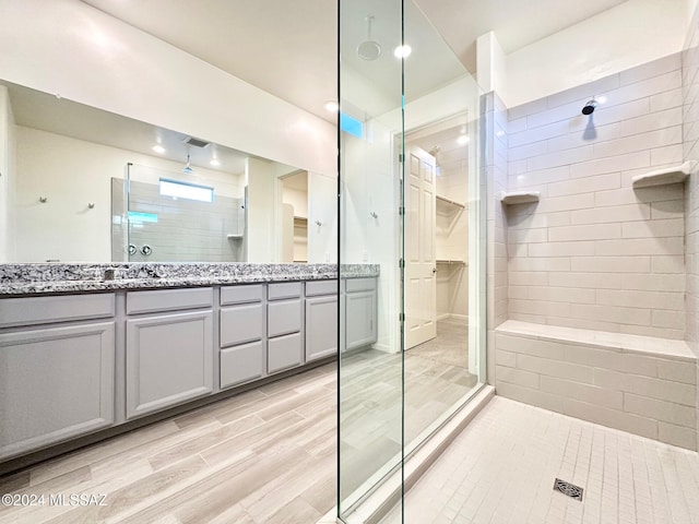 bathroom with hardwood / wood-style floors, vanity, and a tile shower