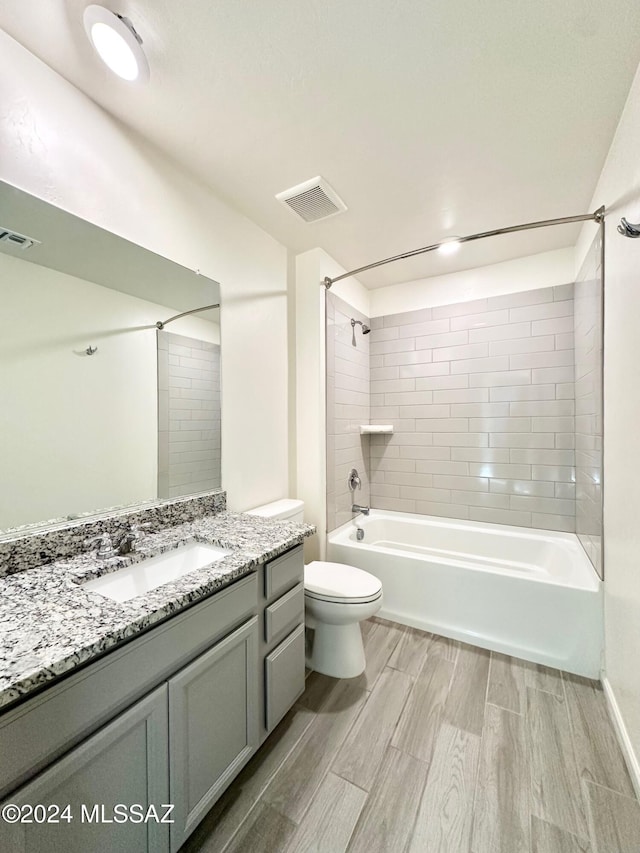 full bathroom featuring tiled shower / bath, vanity, and toilet