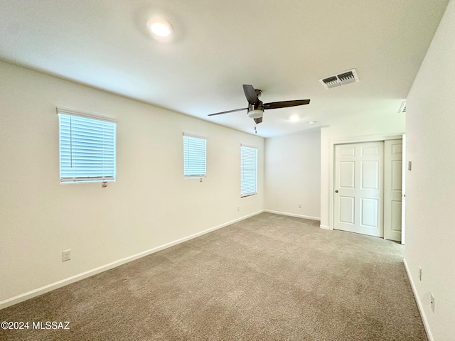 empty room featuring ceiling fan and light carpet